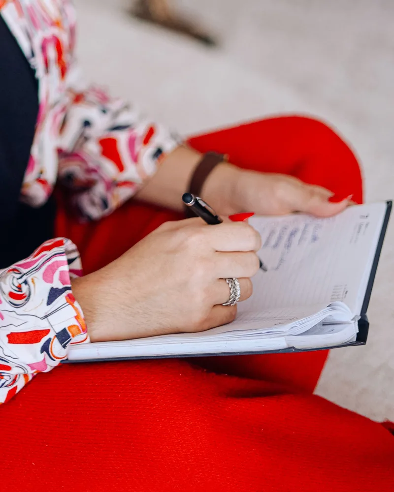 Mãos de Michele anotando em um caderno durante a sessão
